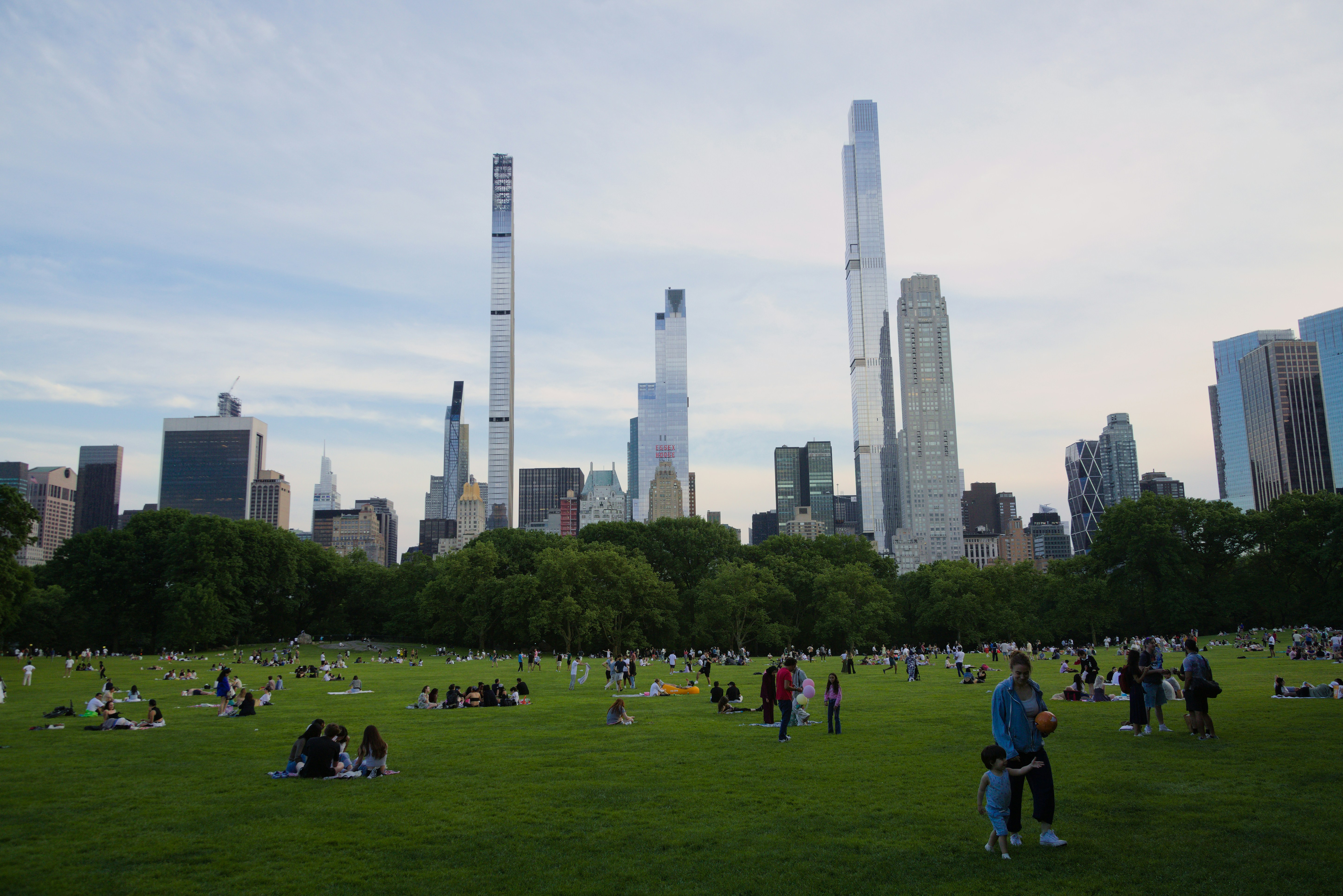 Un gran grupo de personas en un campo con edificios altos en el fondo