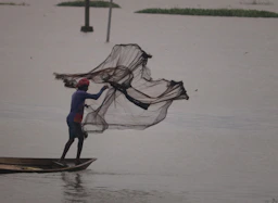 A man standing on a boat holding a fishing net