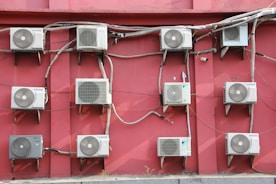 A bunch of air conditioners on a red wall