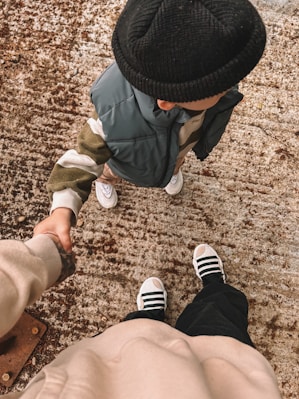 Two people holding hands while standing on a sidewalk