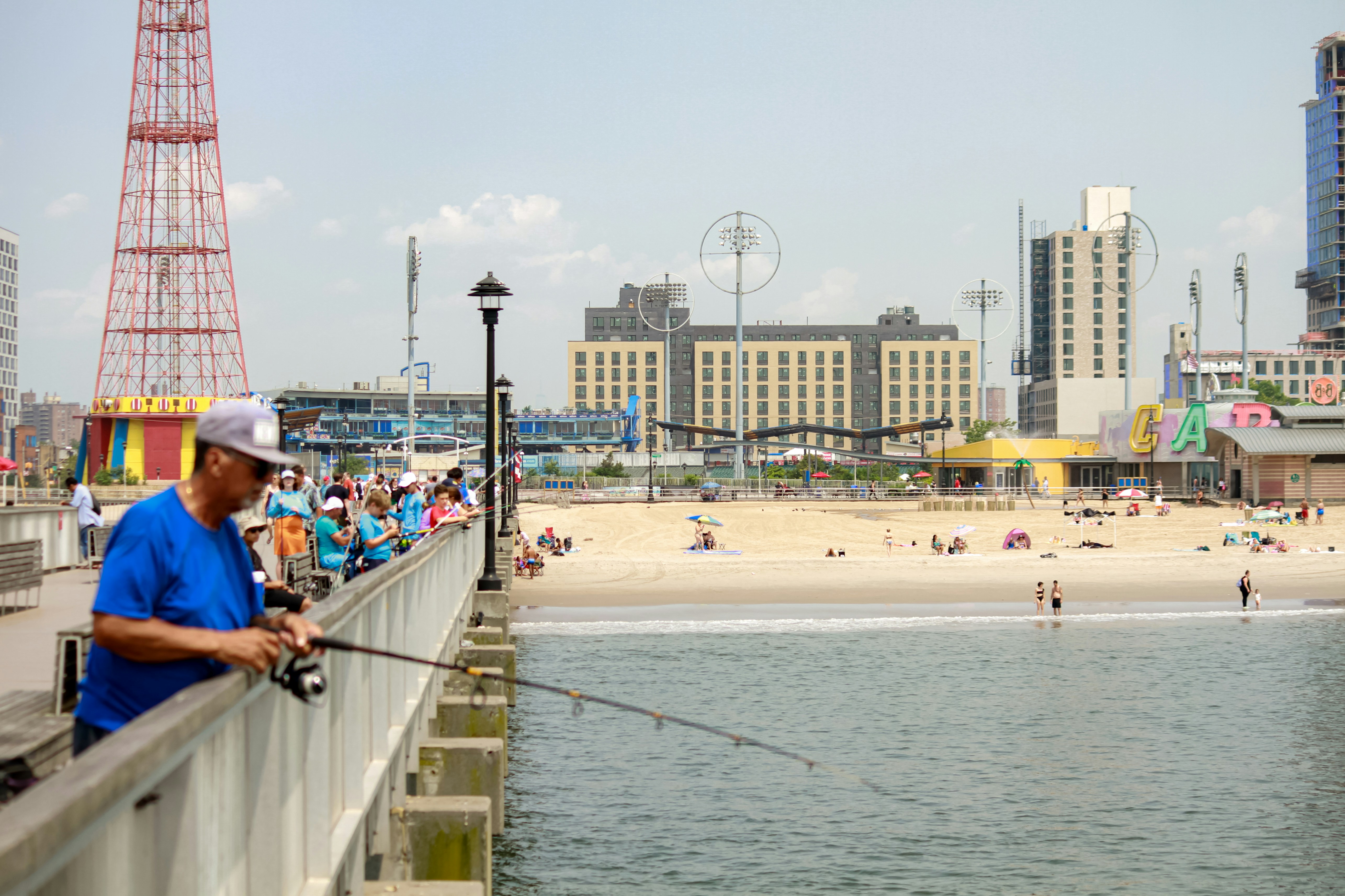 A man fishing on a pier next to the beach