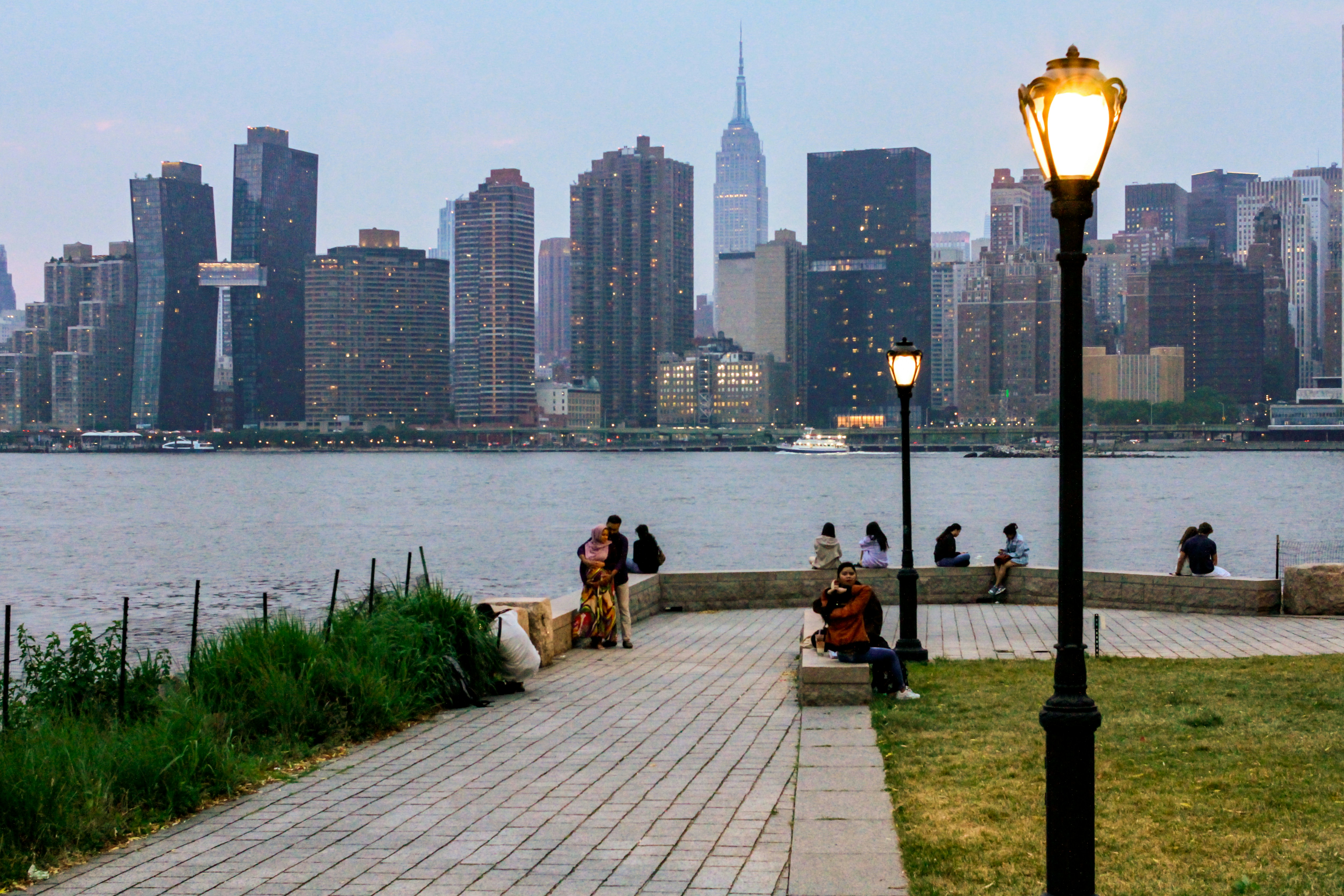 A group of people sitting on a bench next to a body of water