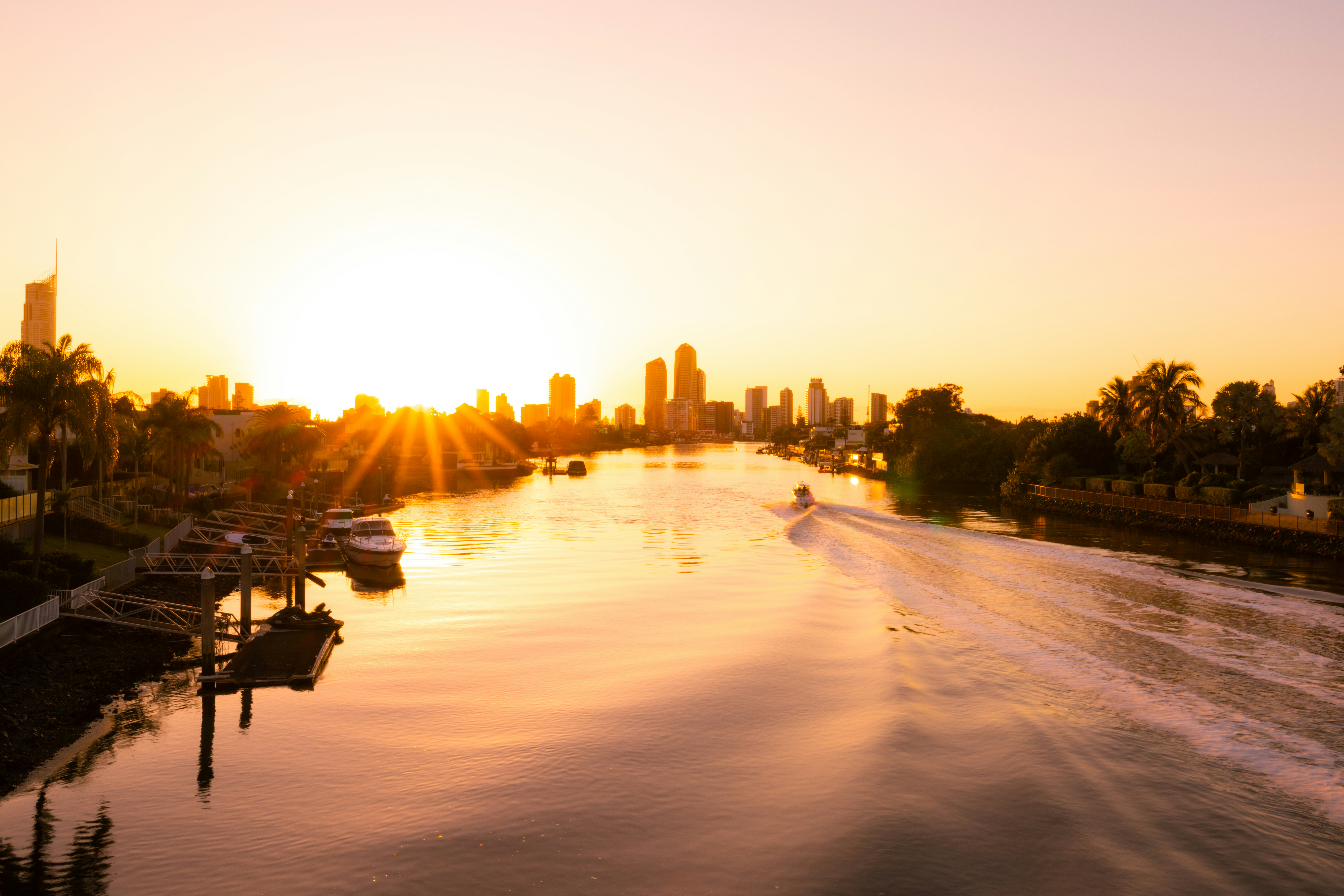 A boat traveling down a river next to a city