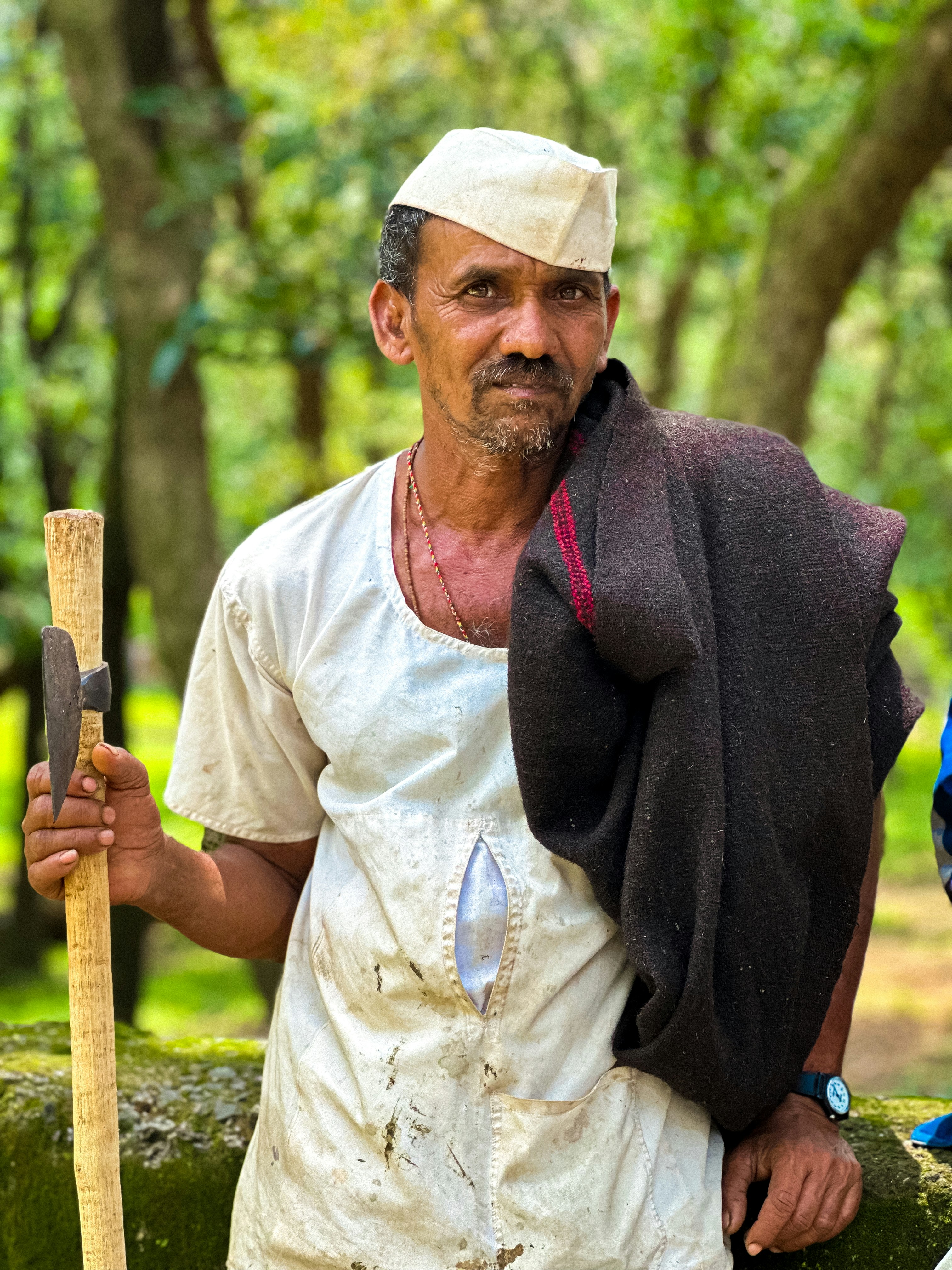 A man with a hat and apron holding a baseball bat