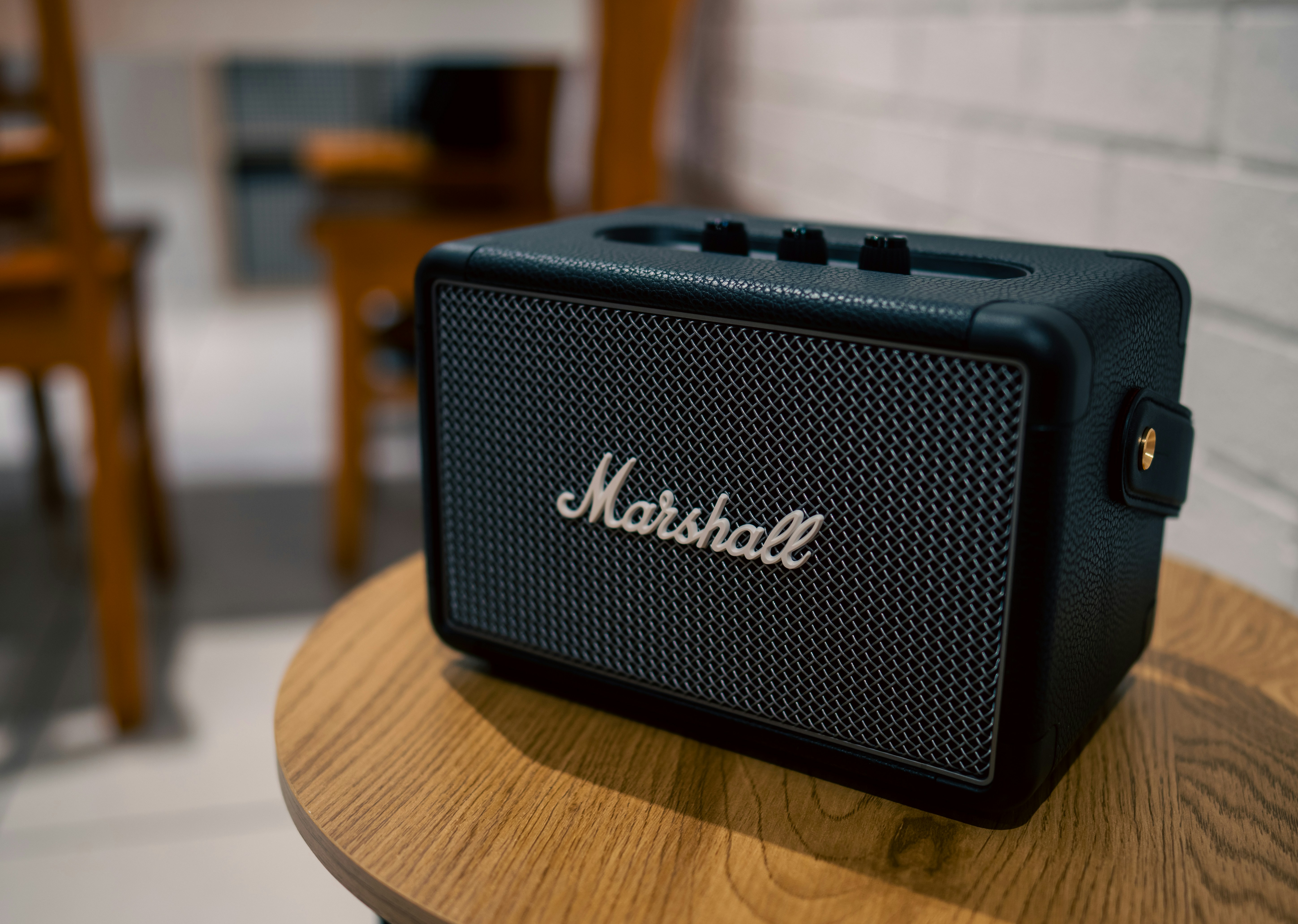A black marshall bluetooth speaker sitting on top of a wooden table