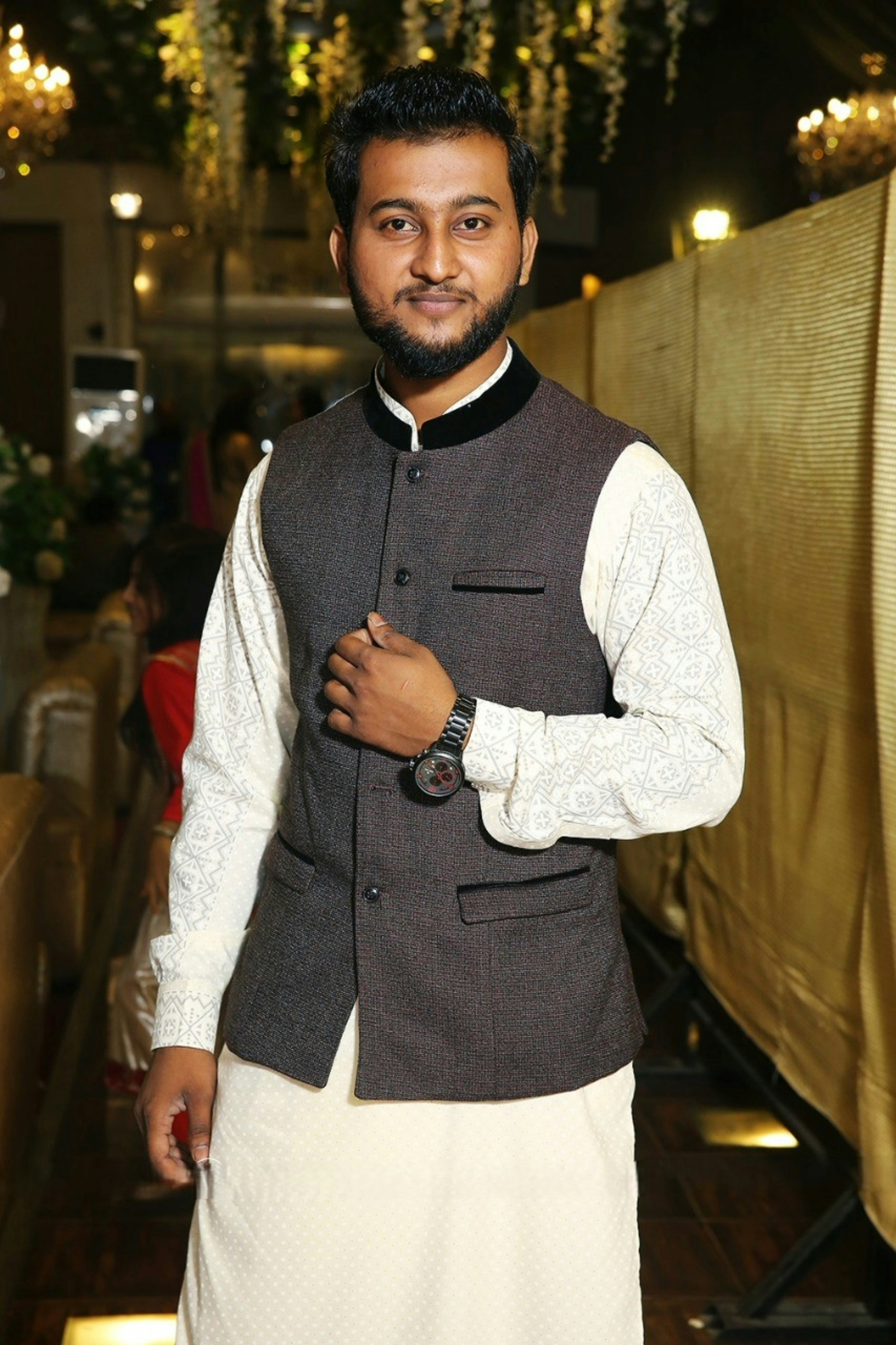 A man standing in a room wearing a vest