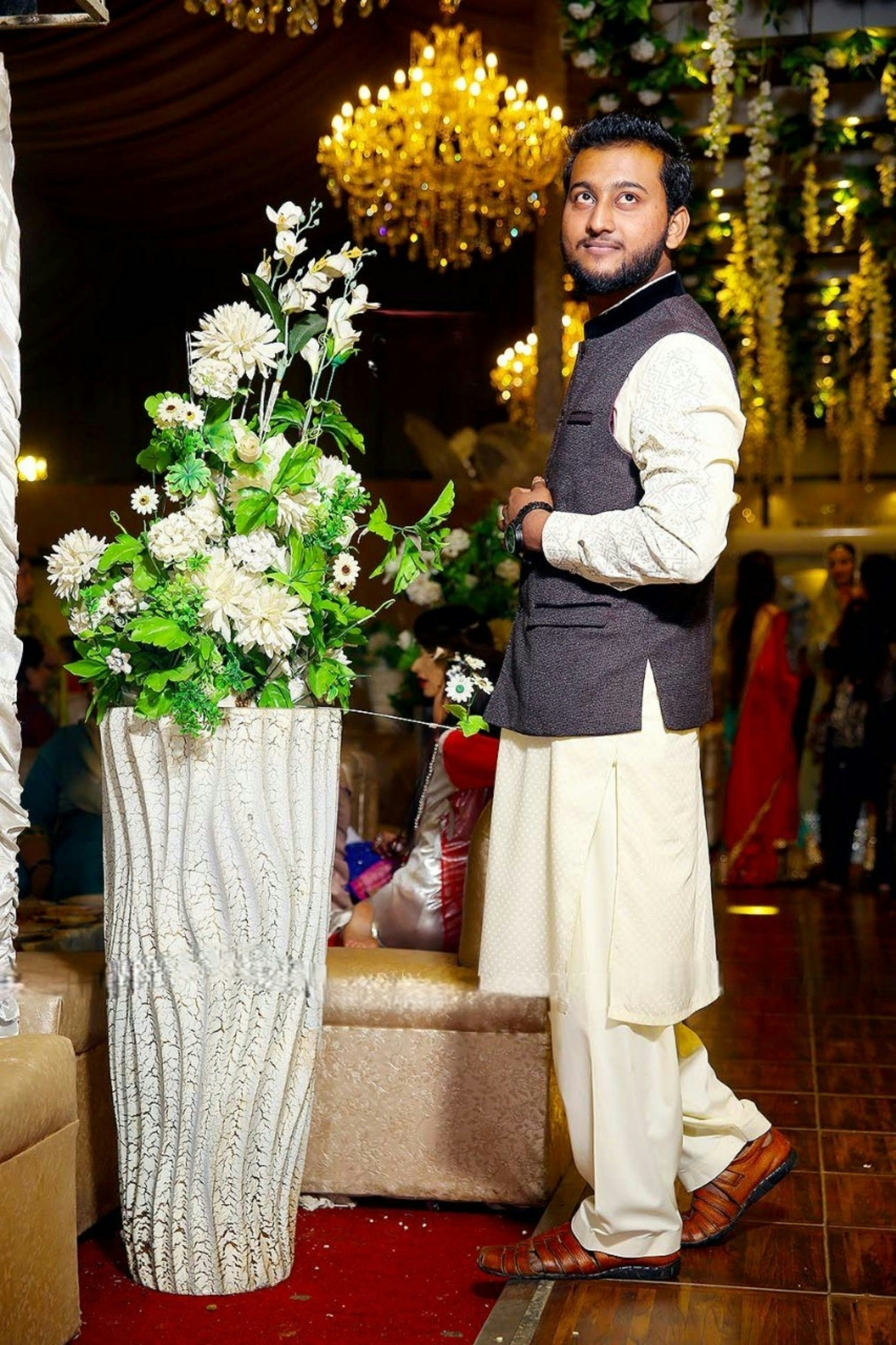 A man standing next to a vase with flowers in it