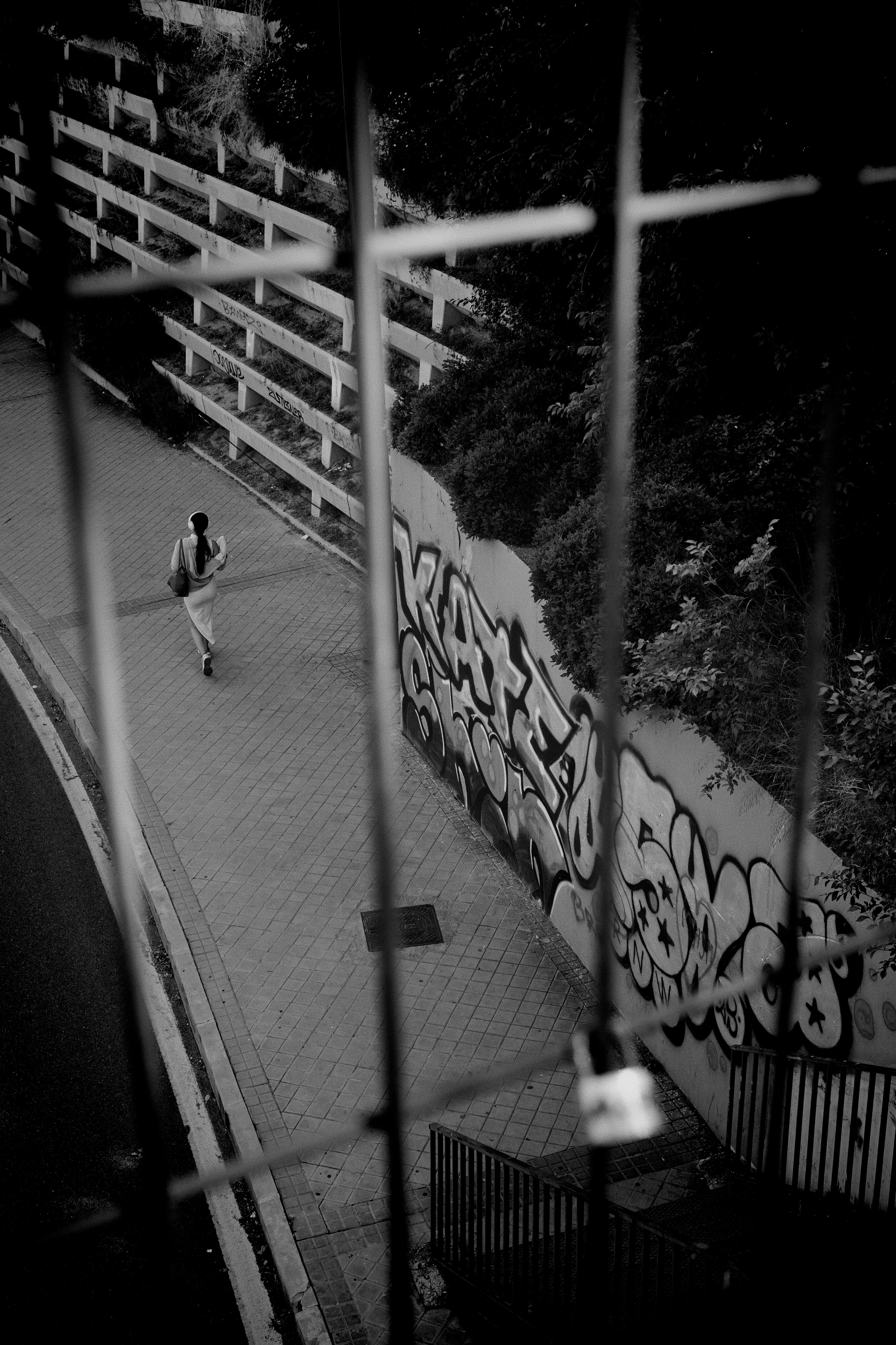 A man riding a skateboard down a street next to a fence
