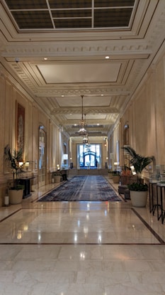 A long hallway with a chandelier and a large rug on the floor