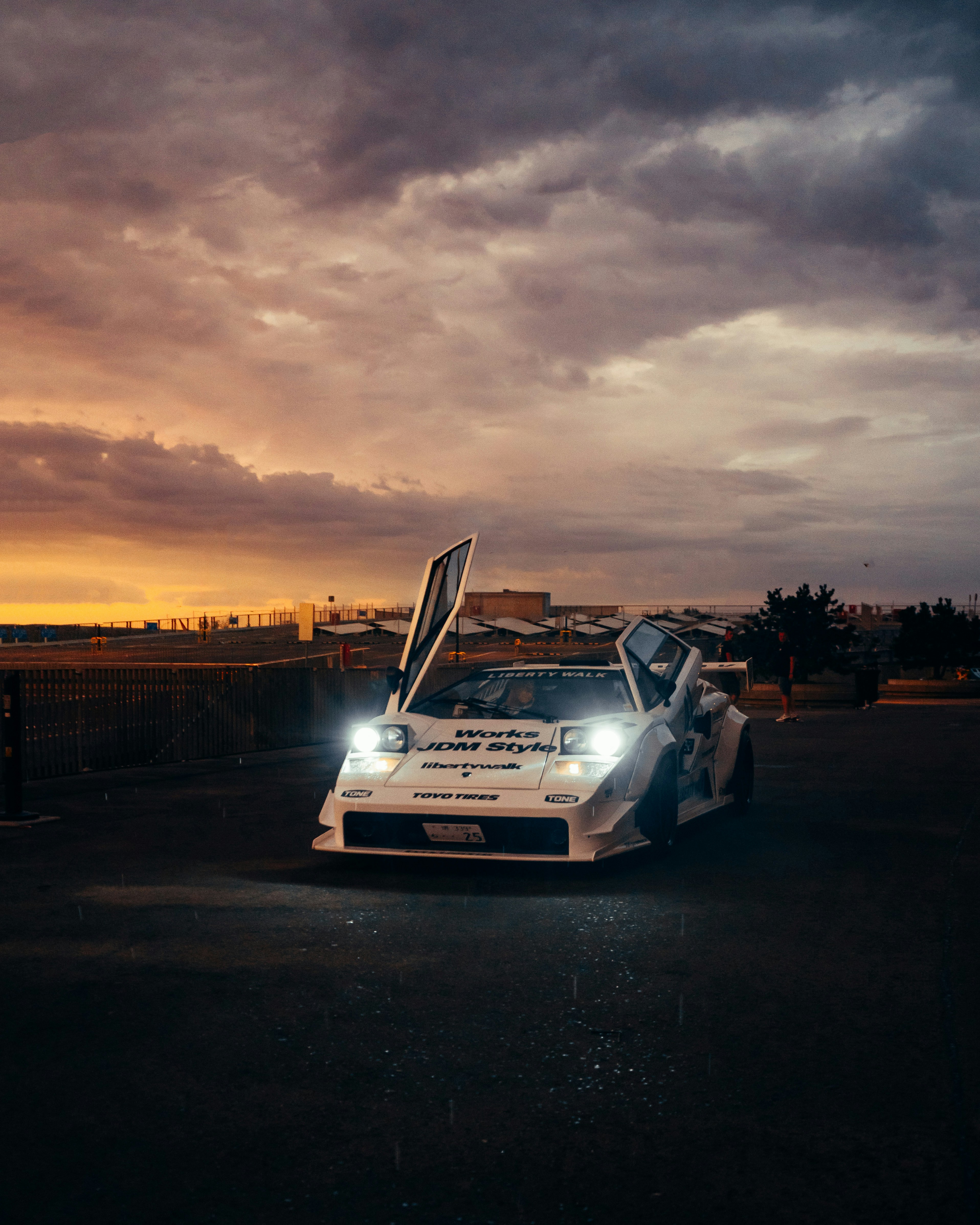 A white car driving down a road under a cloudy sky