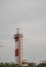 A red and white tower in the middle of a city