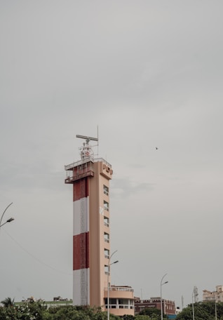 A red and white tower in the middle of a city