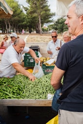 A group of people standing around a table filled with vegetables