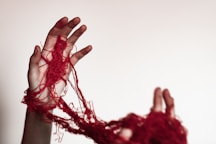 A person with their hands wrapped in red yarn