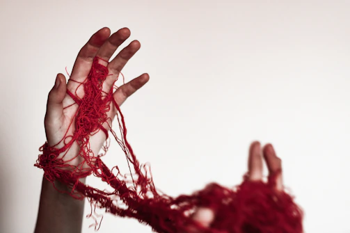 A person with their hands wrapped in red yarn