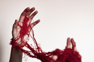A person with their hands wrapped in red yarn