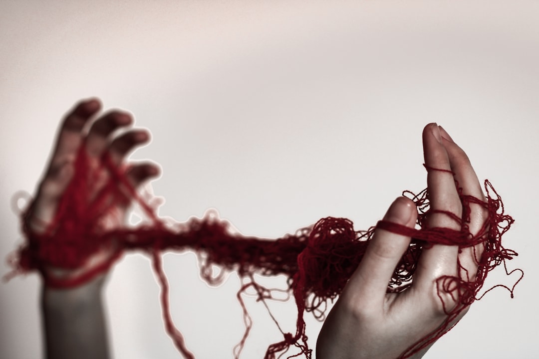A woman holding a red string in her hands,
