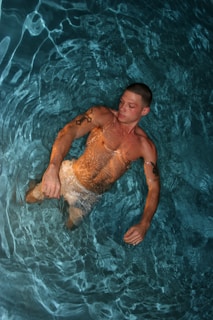 A man swimming in a pool with no shirt on