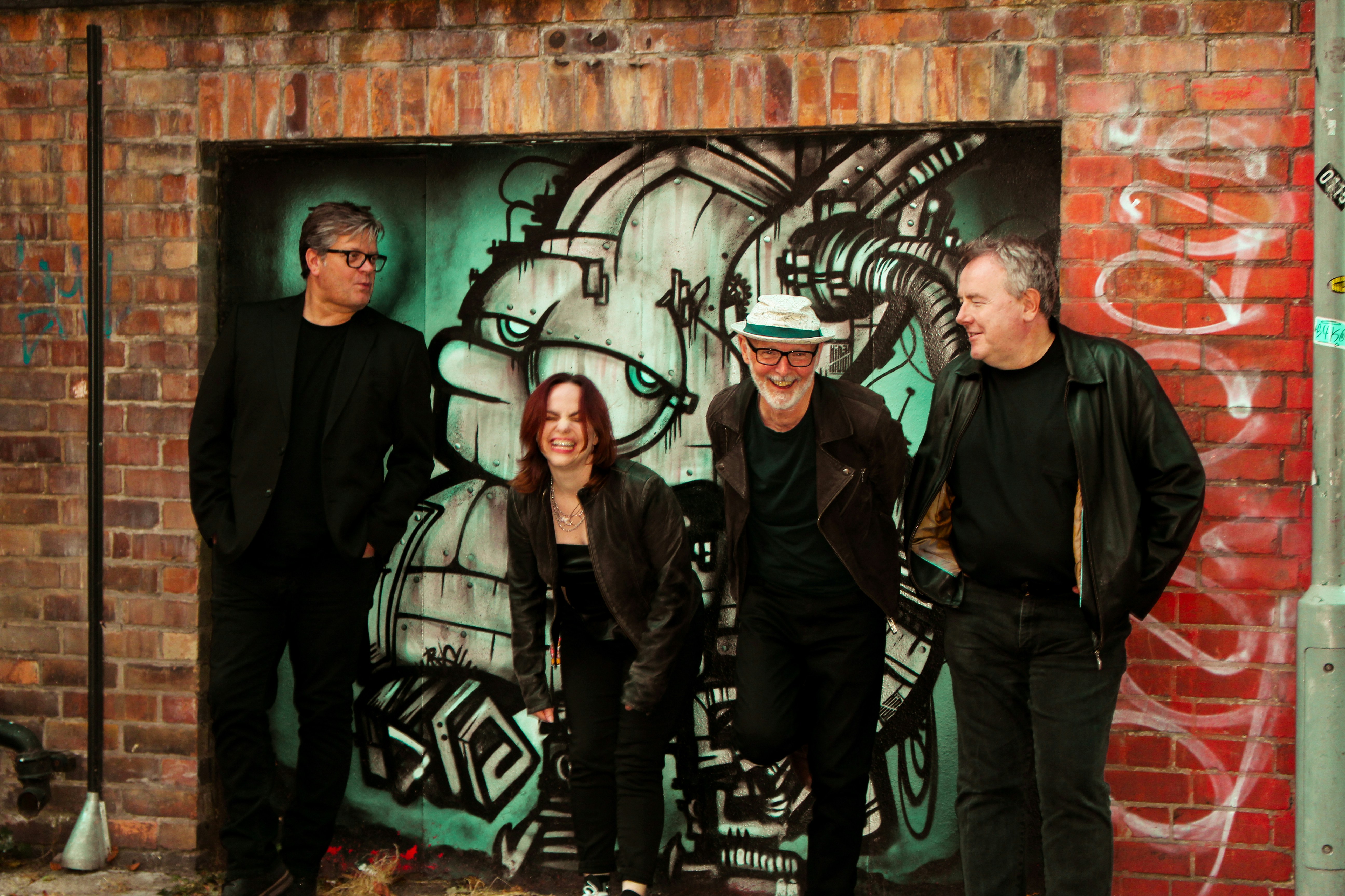 A group of people standing in front of a graffiti covered wall