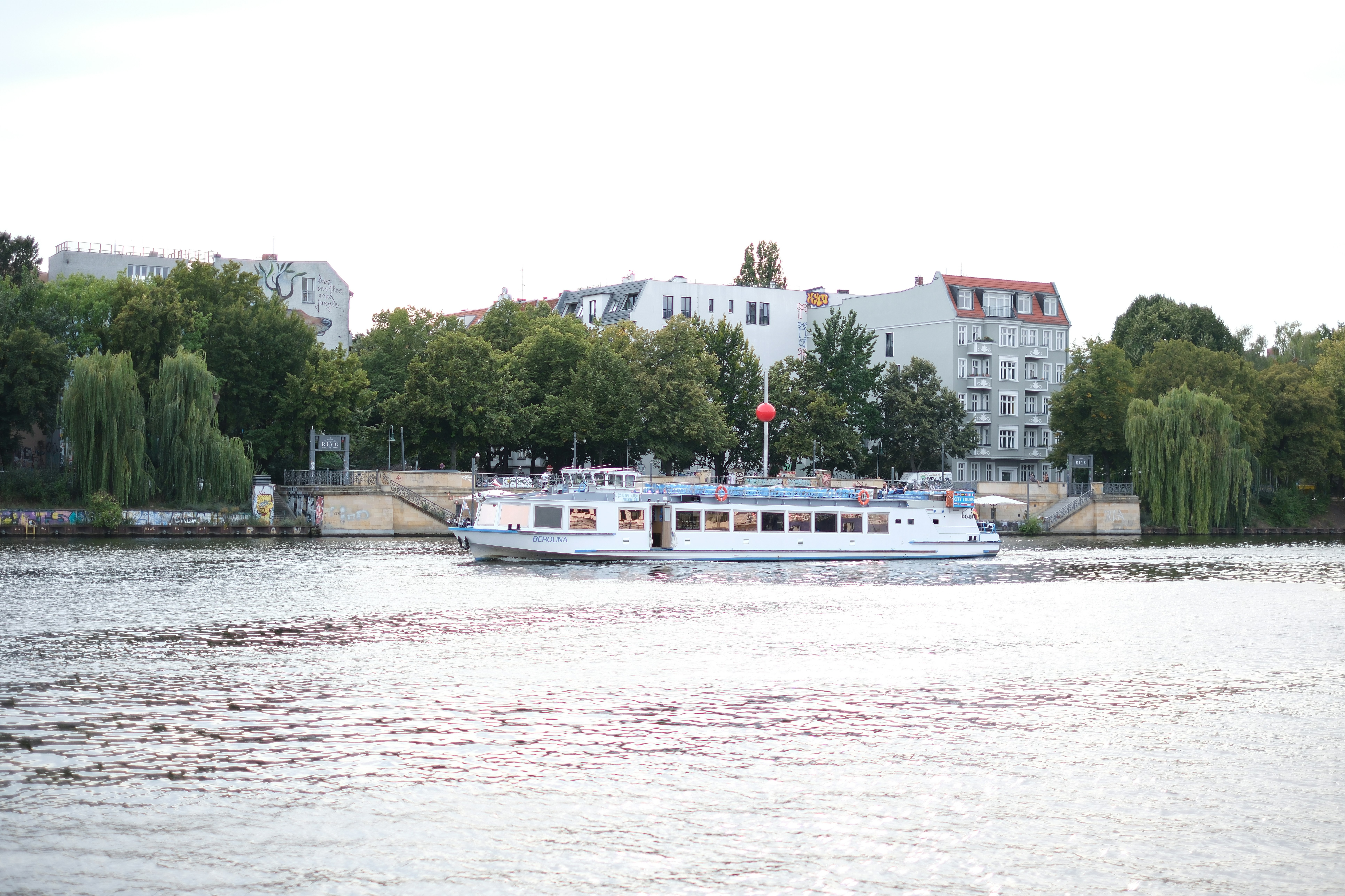 A large white boat floating on top of a river - a-large-white-boat-floating-on-top-of-a-river-jXYkQ1gEhbU