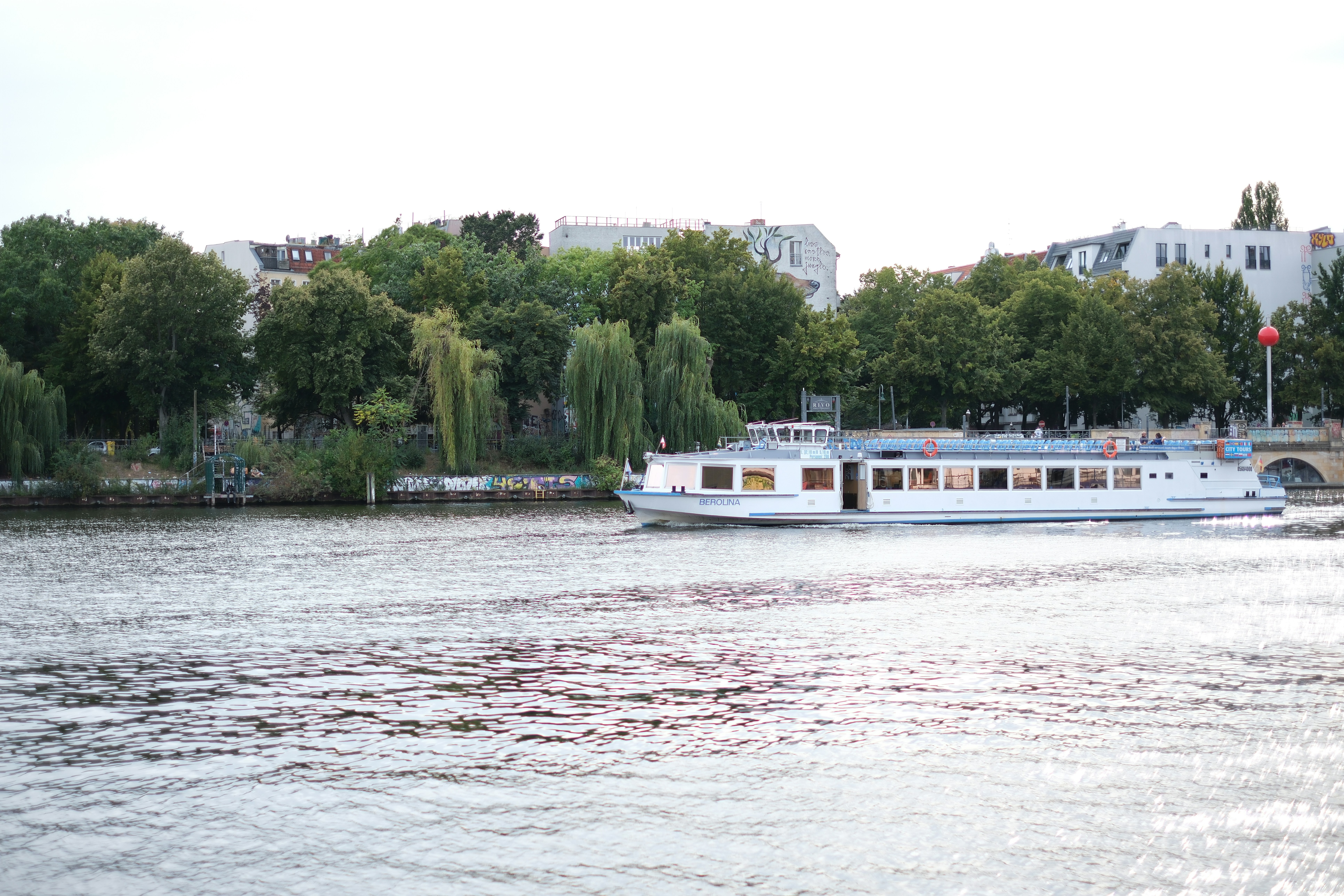 A large white boat floating on top of a river - a-large-white-boat-floating-on-top-of-a-river-2xHOst-WEDo