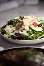 A white bowl filled with a salad on top of a table