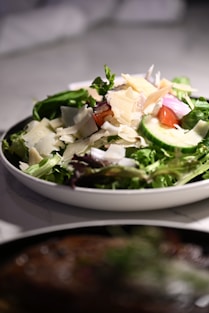 A white bowl filled with a salad on top of a table