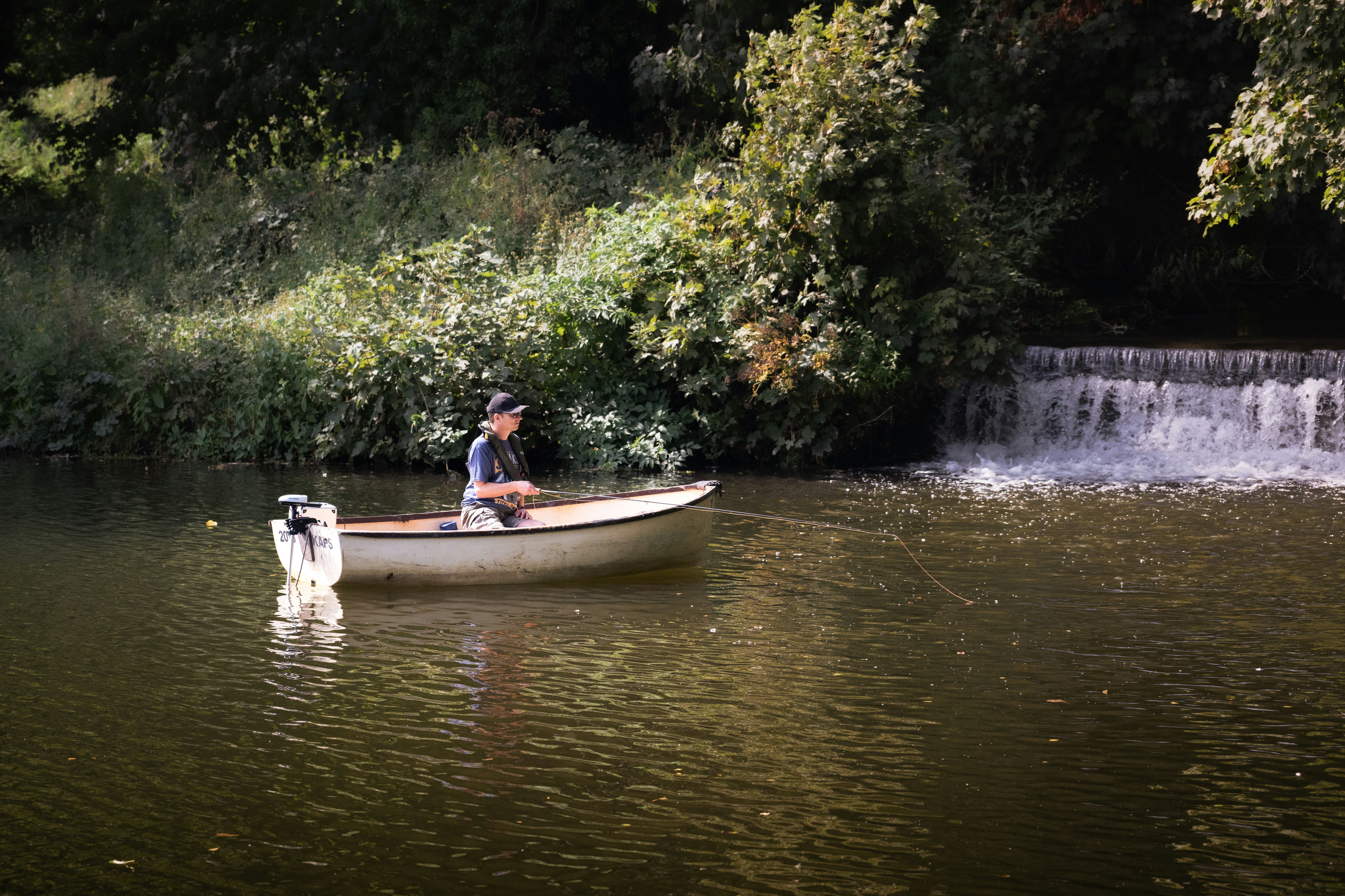 A man in a boat with a dog in the water