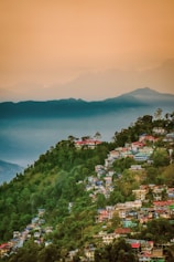 A view of a town on a hill with mountains in the background
