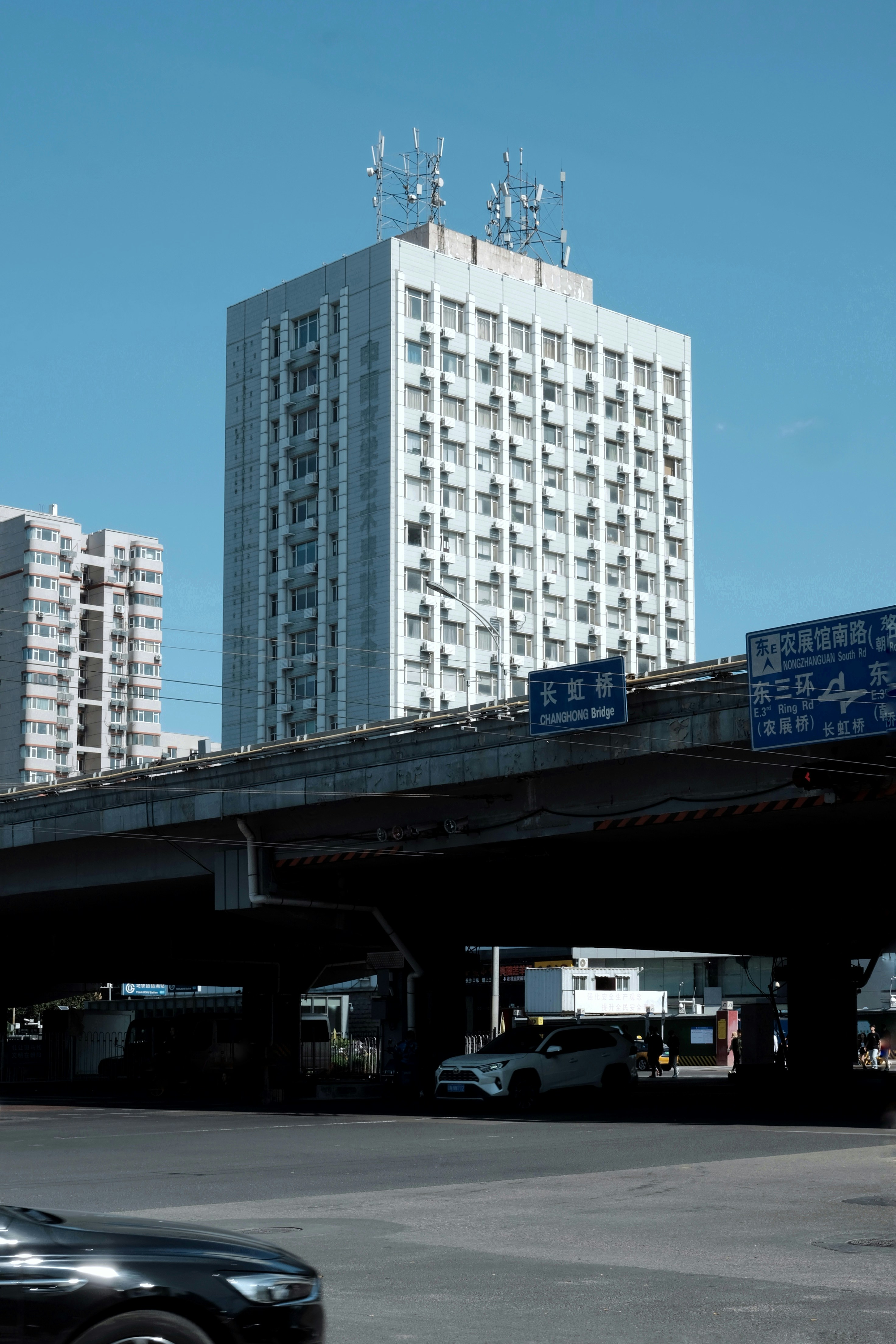 A black car driving down a street next to tall buildings