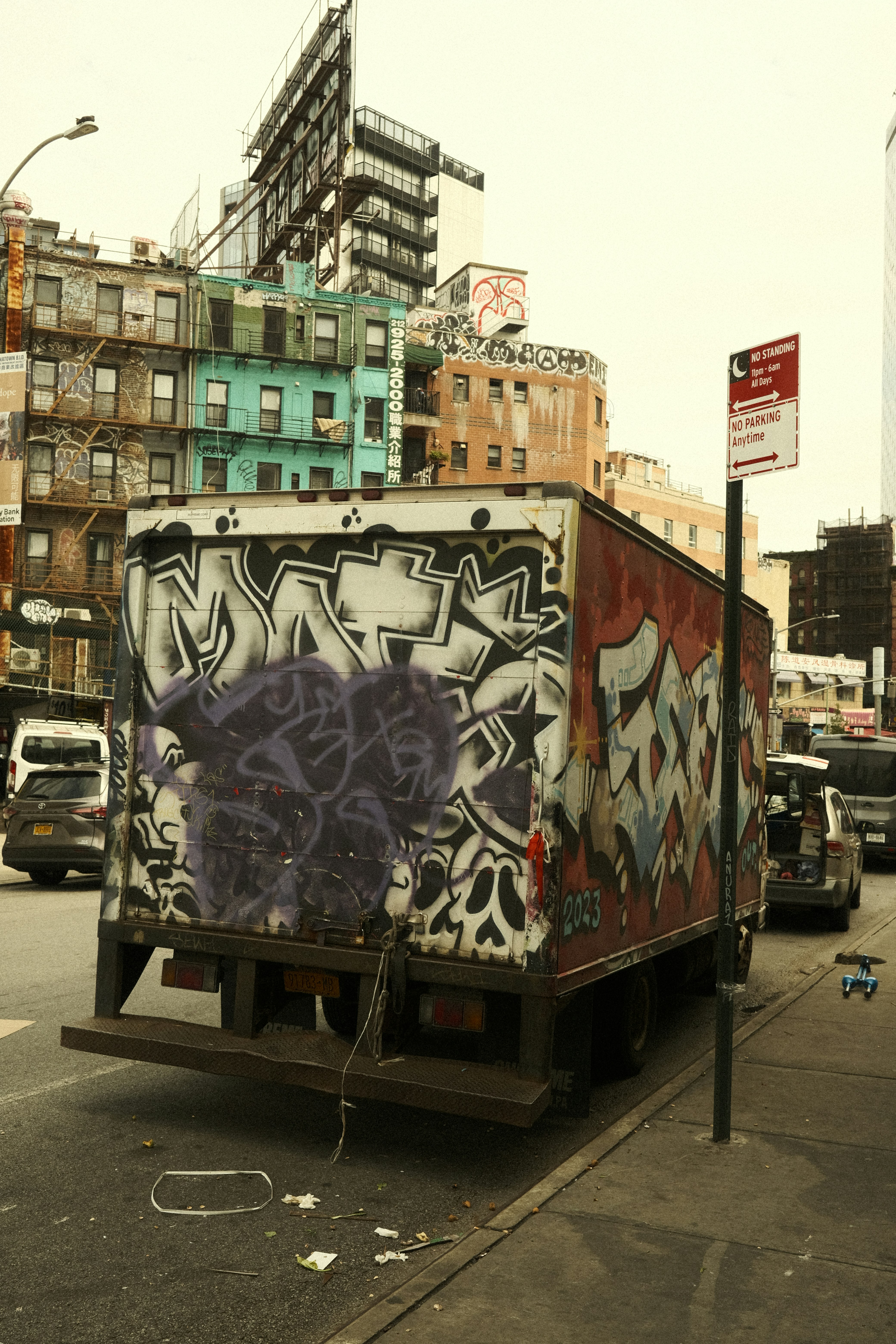 A truck with graffiti on the back driving down a city street