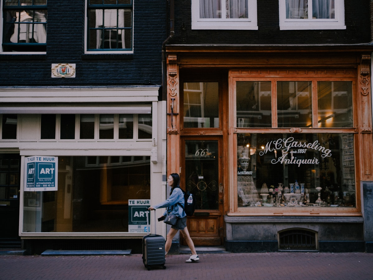 A woman walking down a street past a store front