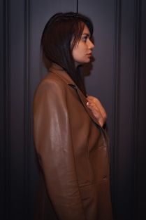 A woman in a brown coat standing in a dark room