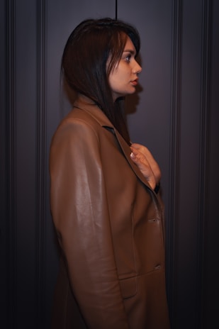 A woman in a brown coat standing in a dark room