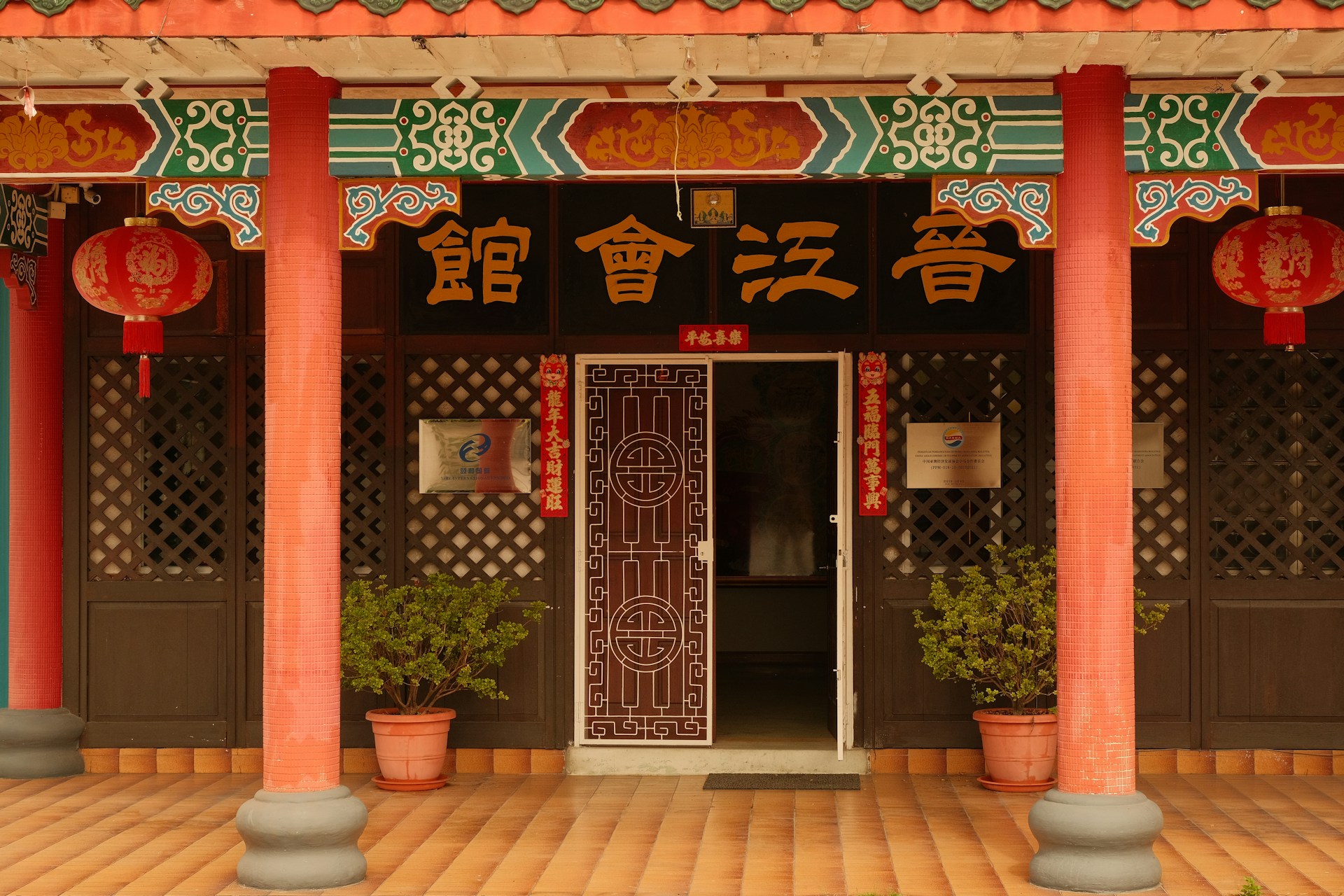 A chinese building with red pillars and green and orange decorations