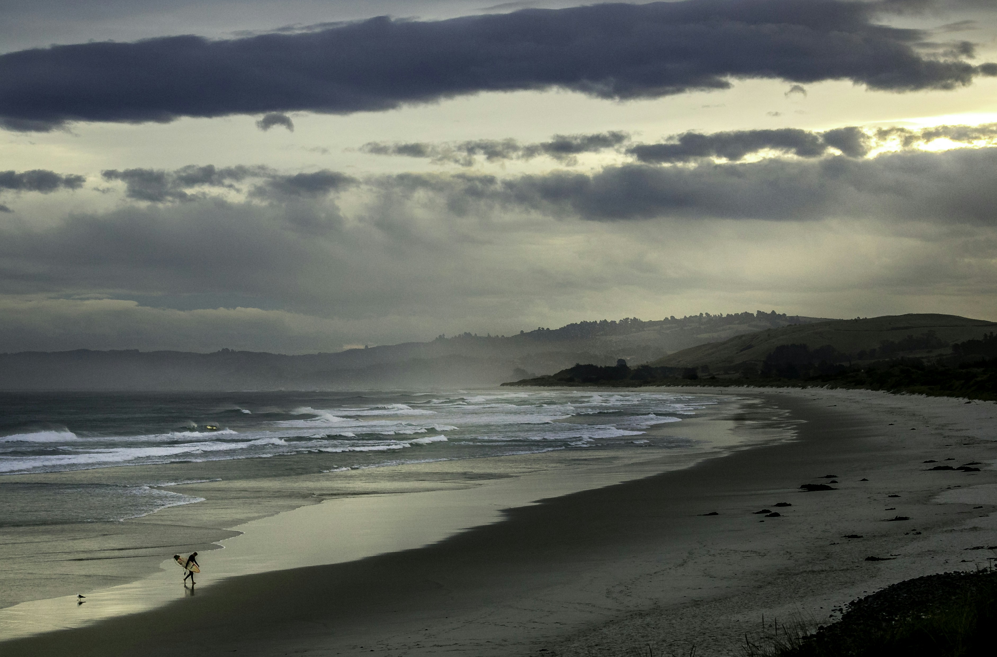 A person standing on a beach next to the ocean