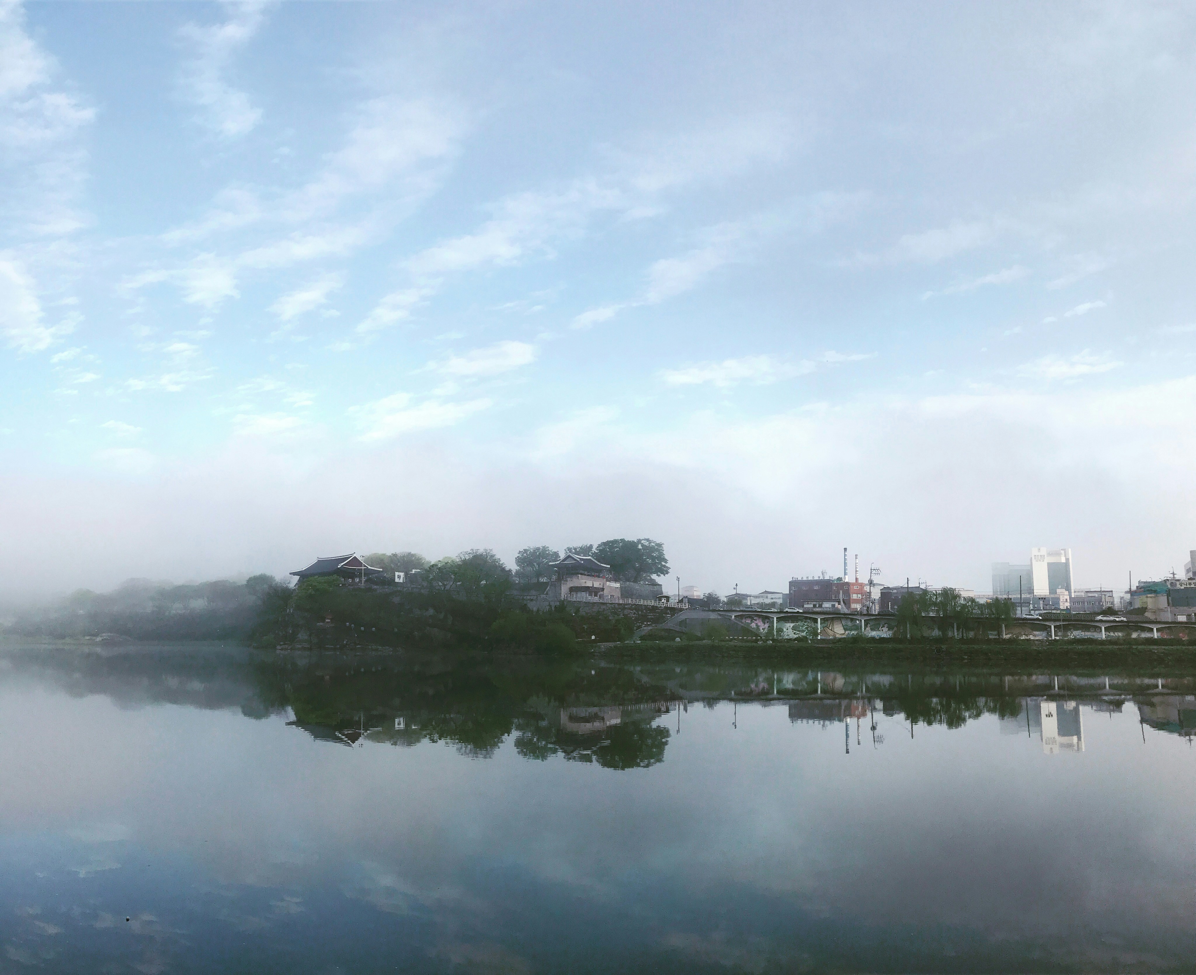Body of water surrounded by lush green forest at dawn, peaceful morning scene. Photo by 태은 김 on Unsplash.