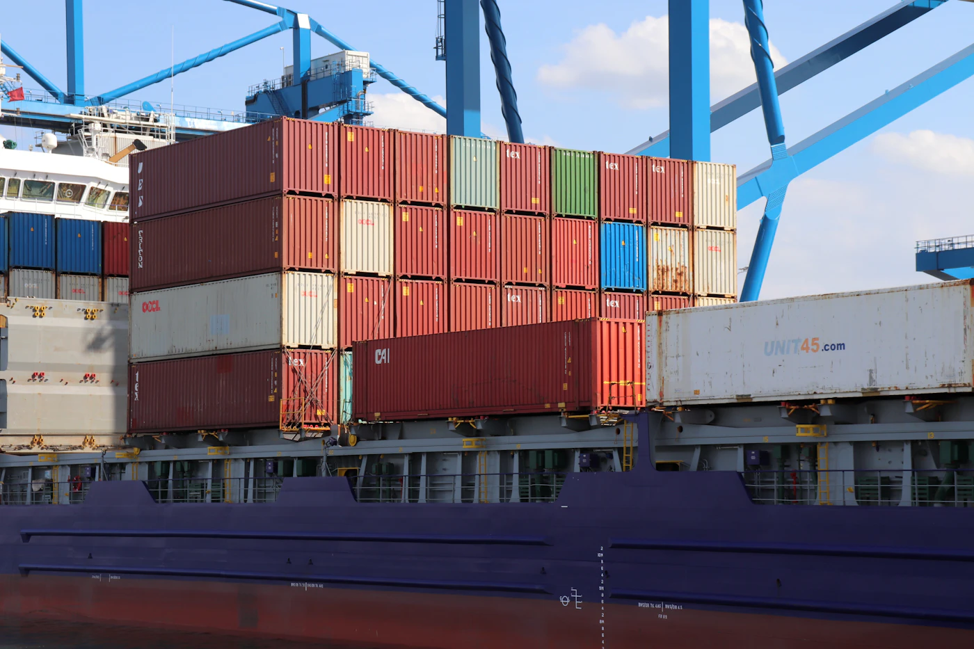 Container vessel alongside a busy freight terminal, illustrating international shipping trade