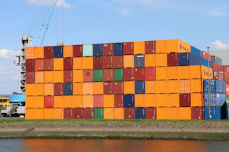 A large stack of containers sitting next to a body of water