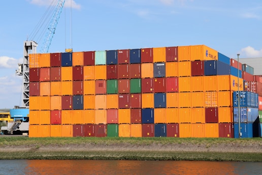 A large stack of containers sitting next to a body of water