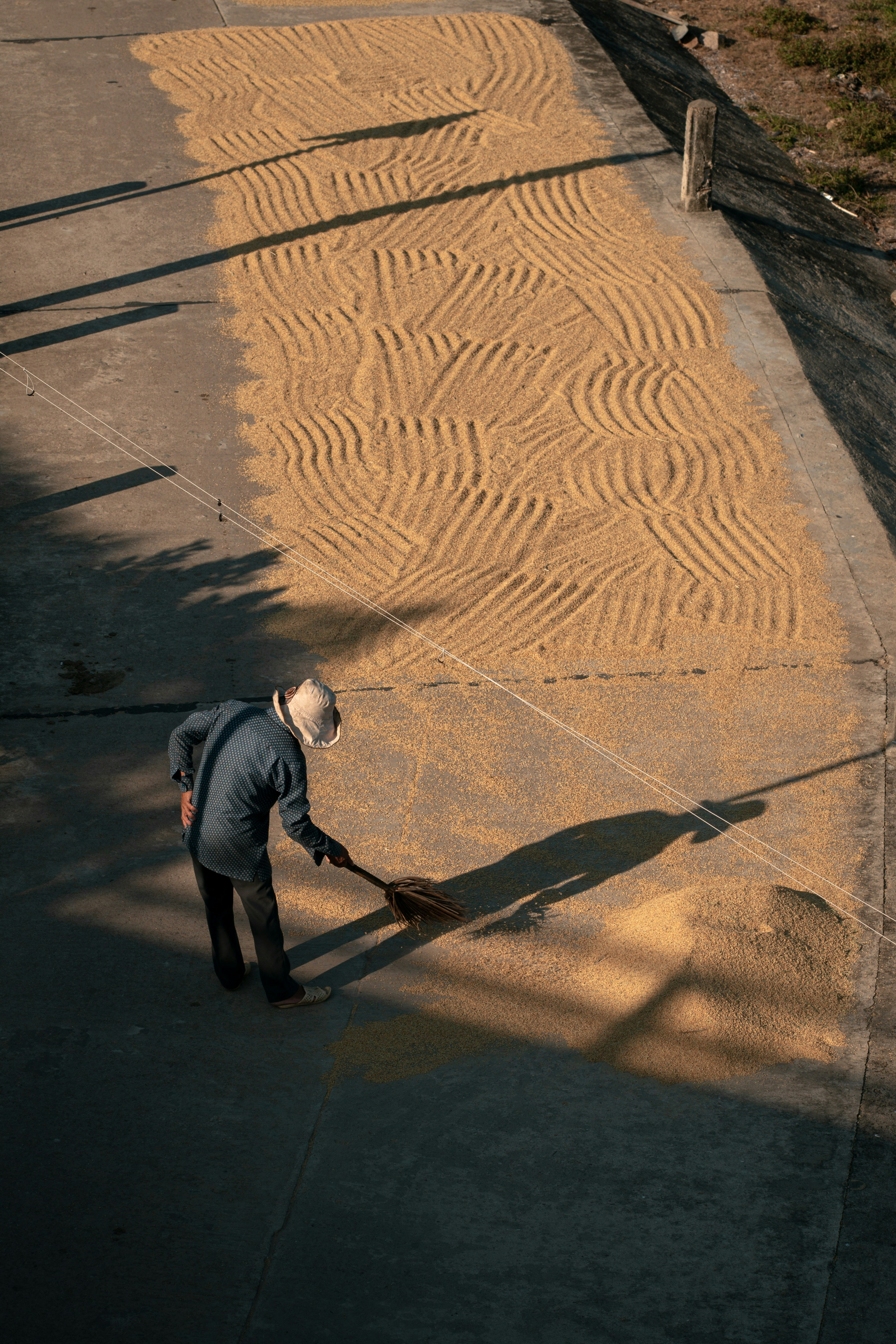 A man is sweeping the sand with a broom