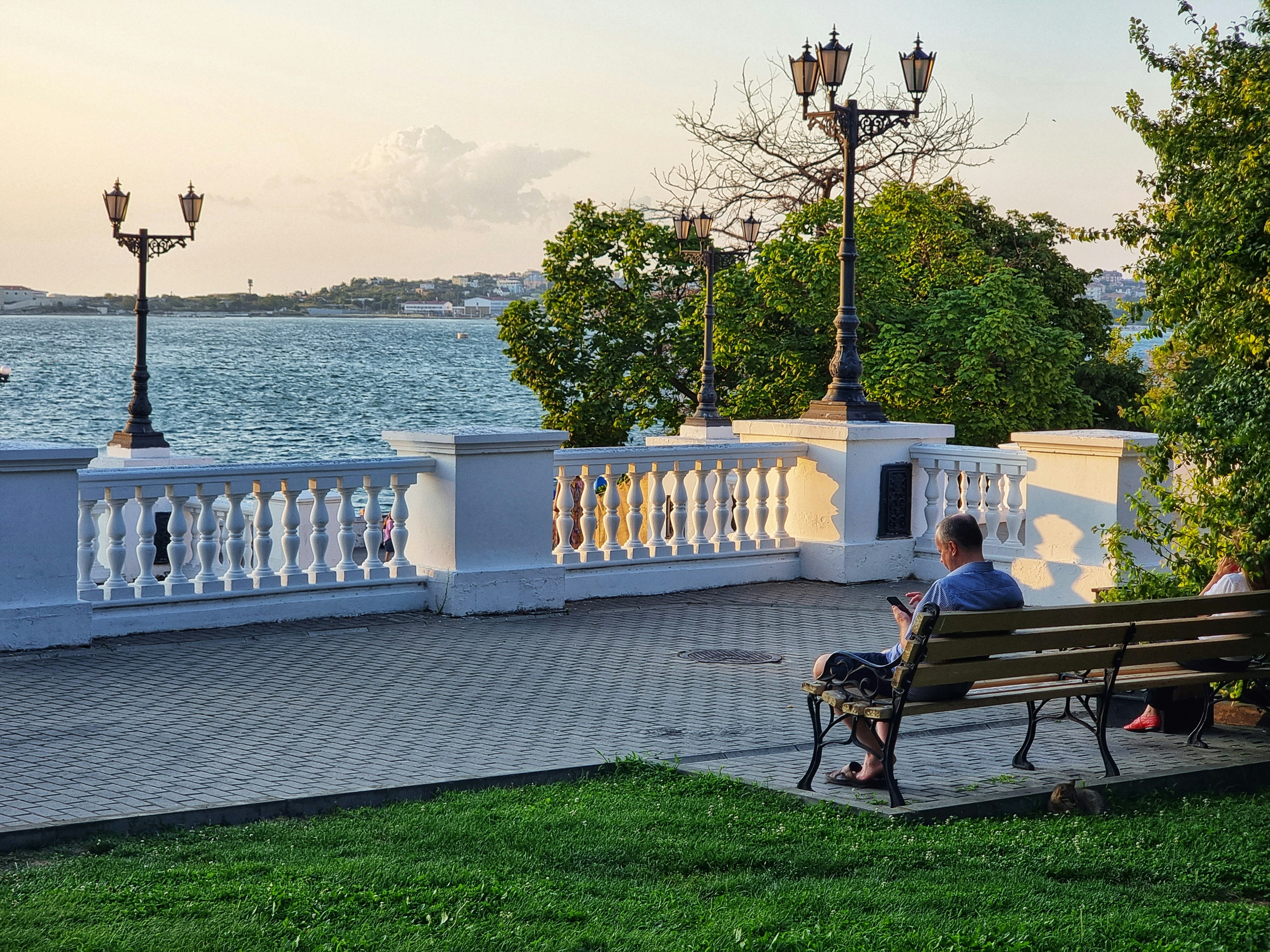 A man sitting on a bench next to a body of water