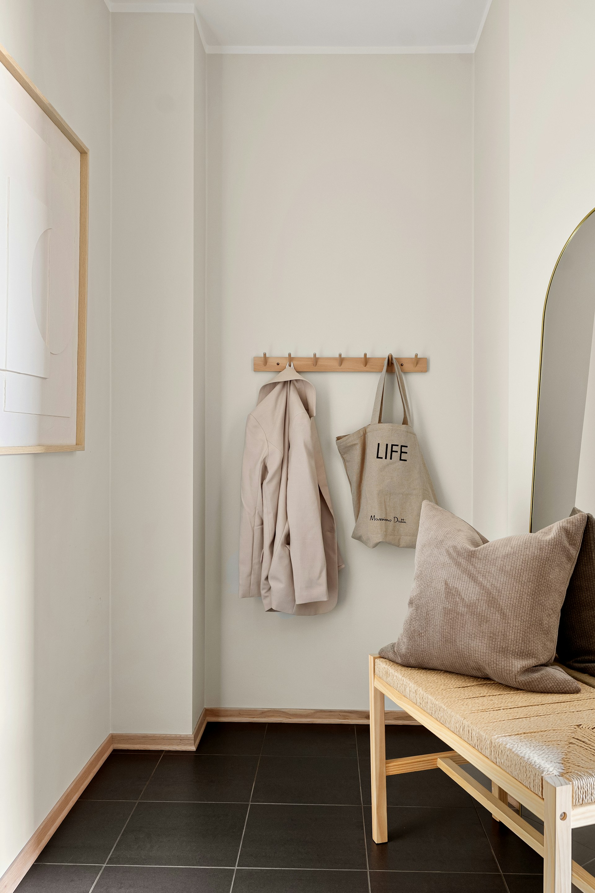 A hallway with a bench, mirror and coat rack