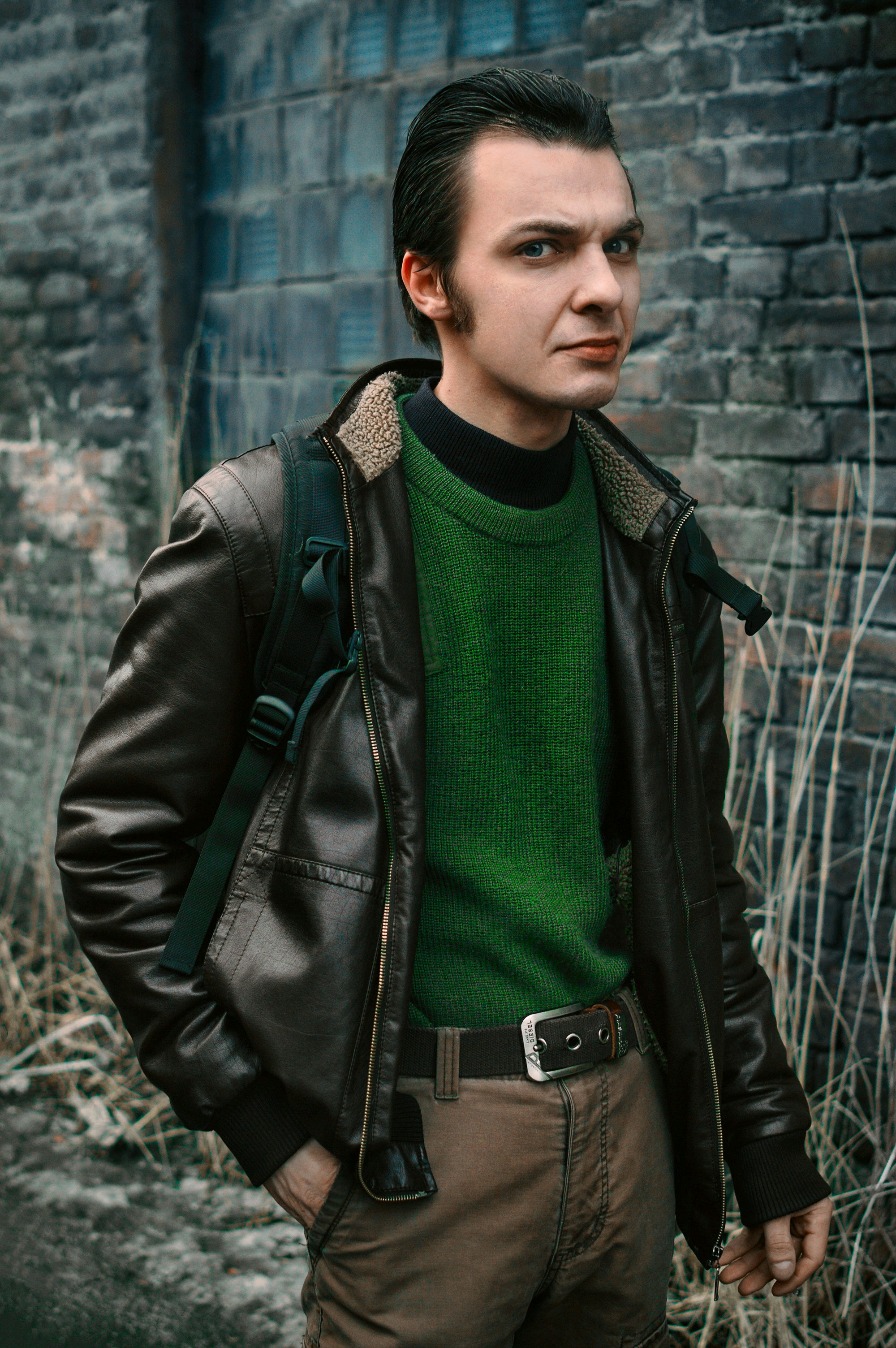A man in a green sweater and a black leather jacket