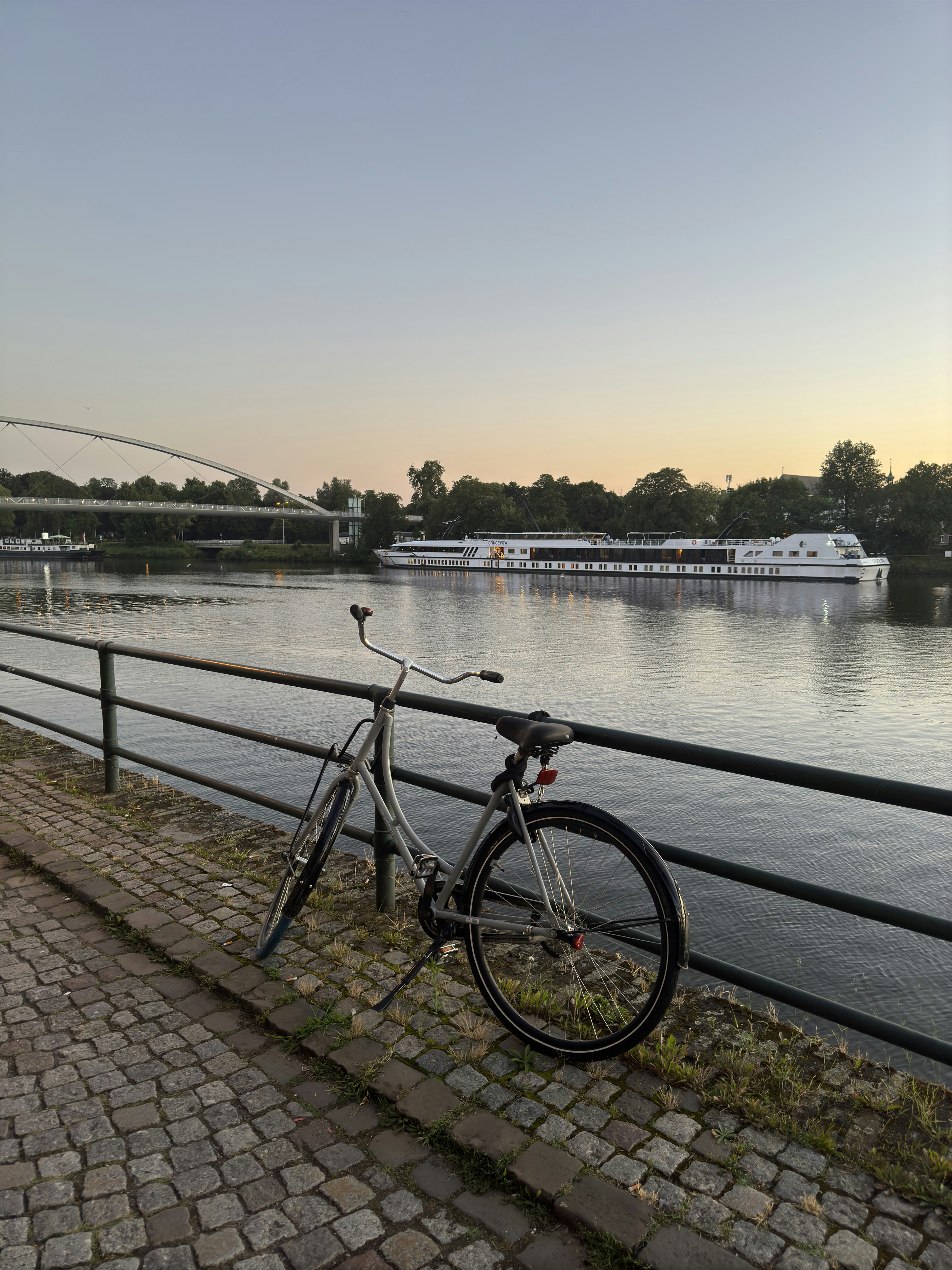 A bike parked next to a fence near a river