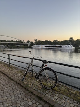 A bike parked next to a fence near a river