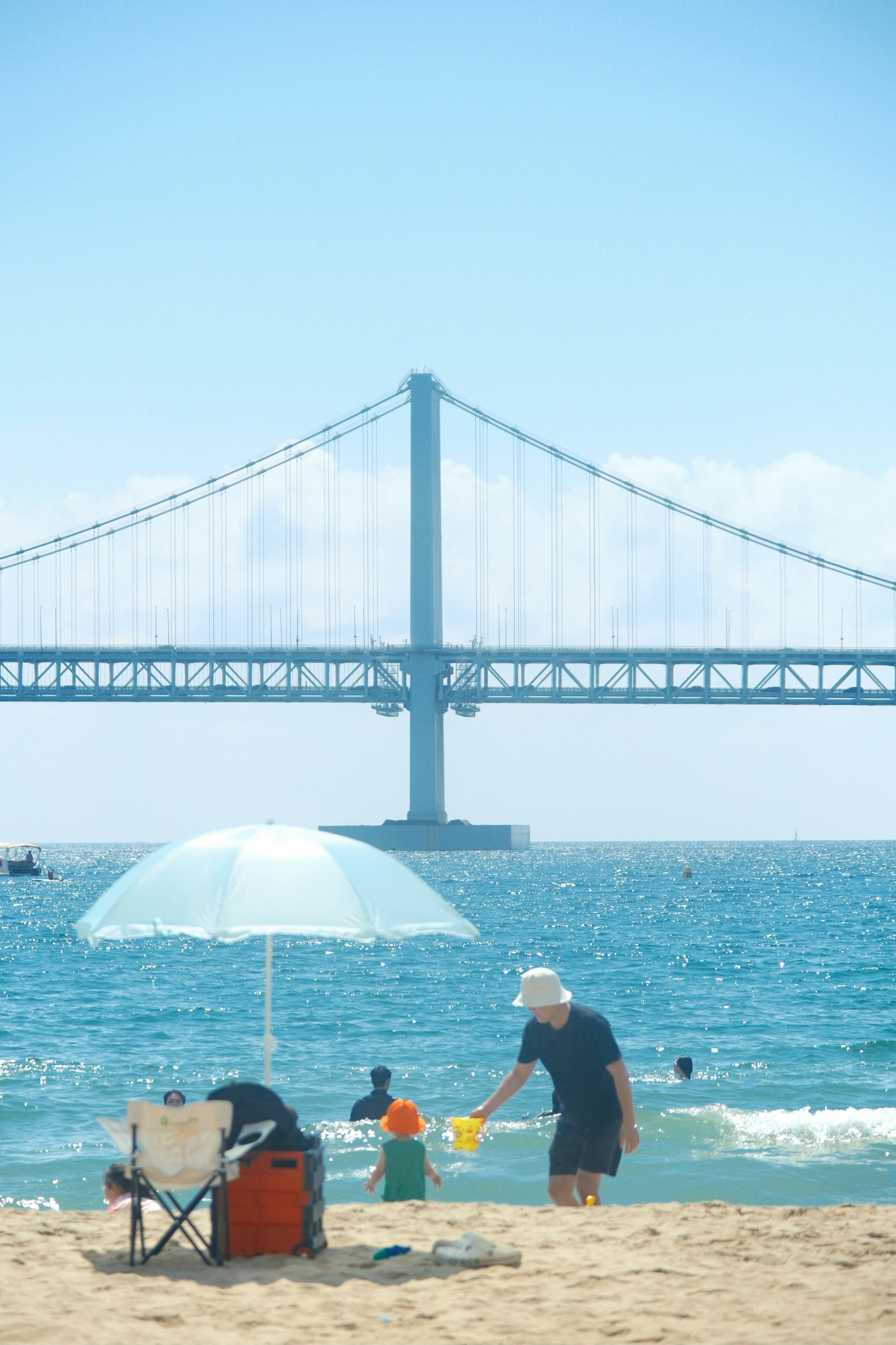 A man standing on top of a sandy beach under a white umbrella