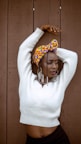 A woman wearing a white sweater and a colorful head scarf