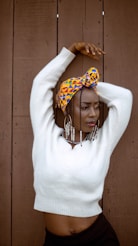 A woman wearing a white sweater and a colorful head scarf