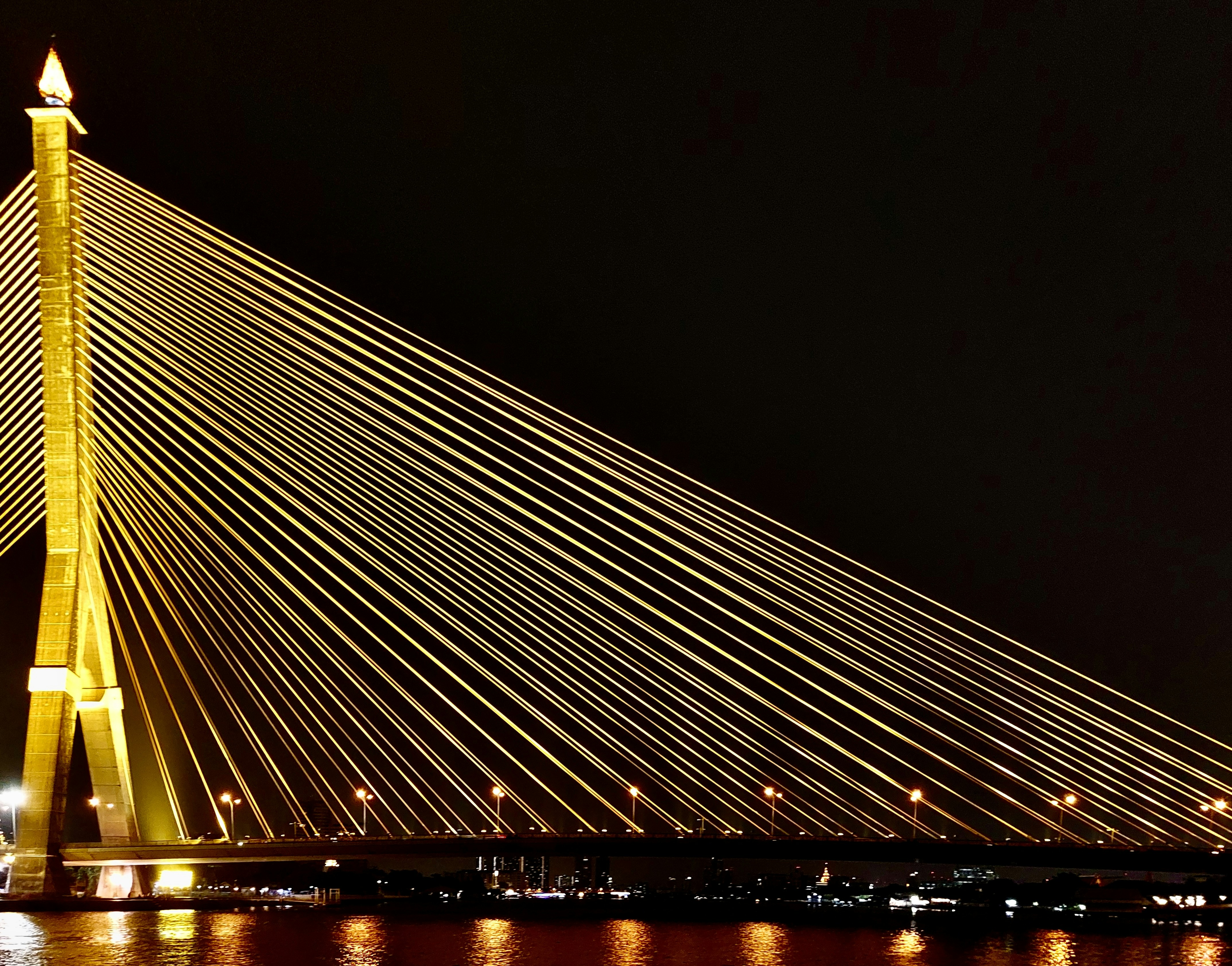 A very long bridge that is lit up at night